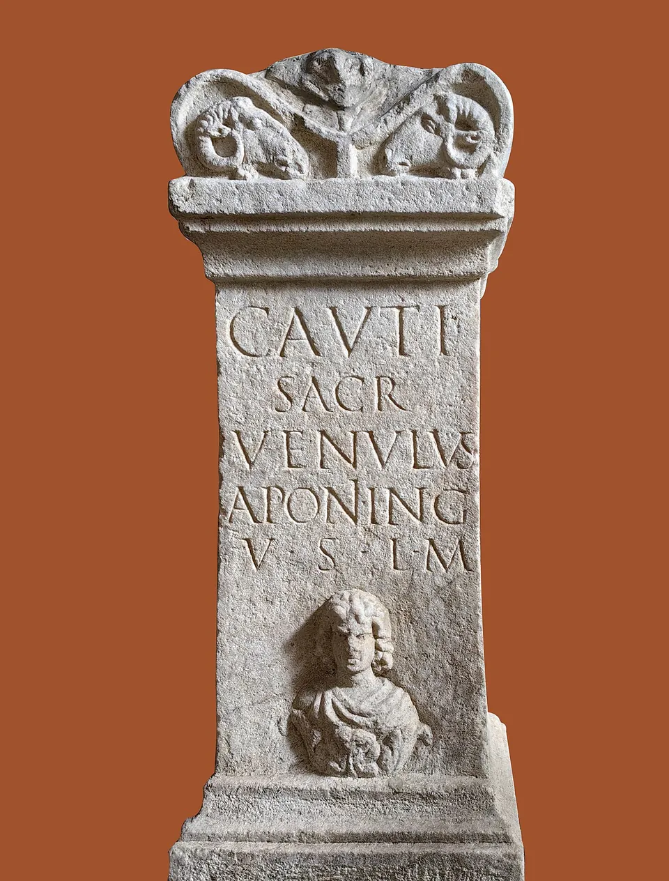 A small stone altar with a scrolled top, carved with a five-line Latin inscription in capitals and a portrait bust in a niche below it; the background is plain reddish brown.