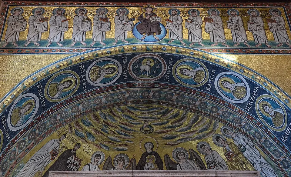 Close view of gold-ground mosaic on the arch of the apse, a band of round medallions each with a named female saint and a lamb at the centre, below a row of standing figures.